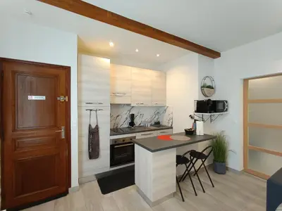 a kitchen with a counter and a table and chairs at Coquet 2 pièces entièrement rénové et climatisé in Cannes