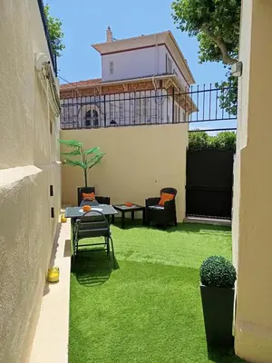 a patio with green grass and a table and chairs at Coquet 2 pièces entièrement rénové et climatisé in Cannes