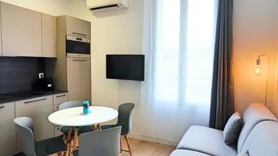 a small living room with a table and a kitchen at Proche Carlton & Croisette, Appartement 101 - Palmazur Vacances in Cannes