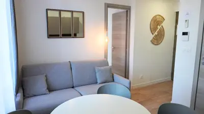 a living room with a blue couch and a table at Proche Carlton & Croisette, Appartement 101 - Palmazur Vacances in Cannes