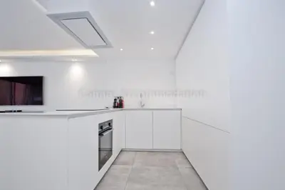 a white kitchen with white cabinets and a ceiling at Blue Bay in Cannes