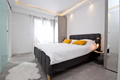 a white bedroom with a large bed with blue pillows at Blue Bay in Cannes