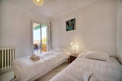 two beds in a room with a window at IMMOGROOM - Fully equipped - Terrace with sea view - AC in Cannes