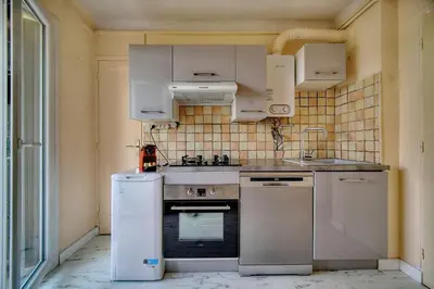 a kitchen with a stove and a sink and a refrigerator at IMMOGROOM - Fully equipped - Terrace with sea view - AC in Cannes