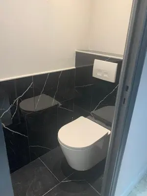 a bathroom with a toilet and a black tiled wall at Appart Le Cannet in Le Cannet