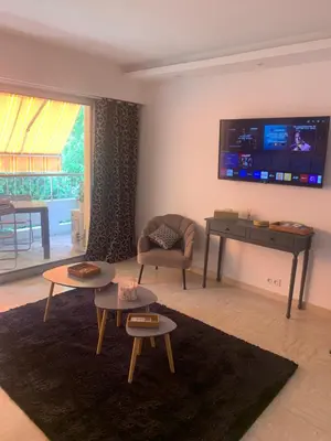 a living room with tables and a tv on the wall at Appart Le Cannet in Le Cannet