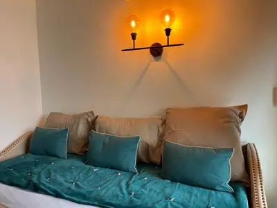 a couch with two pillows and two lights on the wall at Superbe appartement une chambre vue mer piscine tennis in Cannes