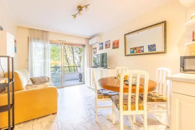 a living room with a table and a couch at LB Vacation Rentals I Cannes Croisette, Large Terrace, Free Parking, Beaches in Cannes