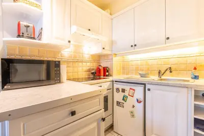 a kitchen with white cabinets and a sink and a refrigerator at LB Vacation Rentals I Cannes Croisette, Large Terrace, Free Parking, Beaches in Cannes
