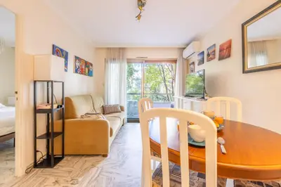 a living room with a table and a couch at LB Vacation Rentals I Cannes Croisette, Large Terrace, Free Parking, Beaches in Cannes