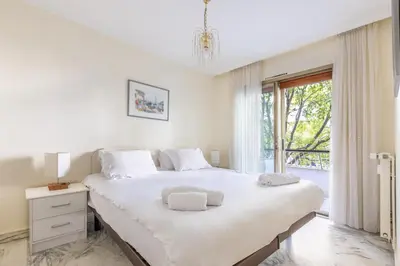 a white bedroom with a large bed and a window at LB Vacation Rentals I Cannes Croisette, Large Terrace, Free Parking, Beaches in Cannes