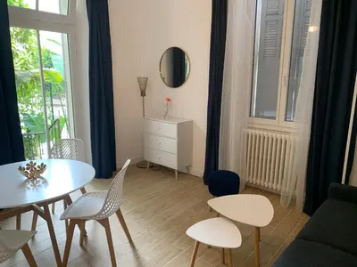 a living room with a table and chairs at Villa Les Fougeres 2p jardin parking in Cannes