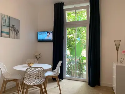 a dining room with a table and chairs and a window at Villa Les Fougeres 2p jardin parking in Cannes