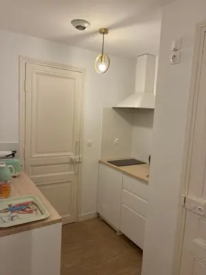 a kitchen with white cabinets and a white door at Villa Les Fougeres 2p jardin parking in Cannes