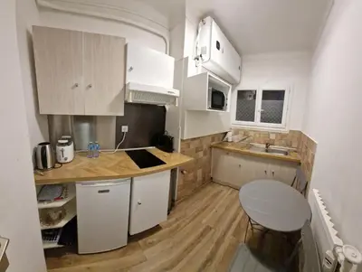 a small kitchen with white cabinets and a table at Studio confortable 10 min du Palais des festivals in Cannes