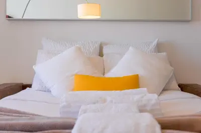 a bed with white pillows and a yellow pillow at Croisette Beach & Palace in Cannes