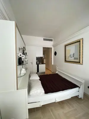 a white bedroom with a large bed and a table at CosyGray512 in Cannes