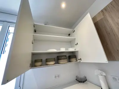 a kitchen with white walls and white shelves at Maison de ville tout confort à Cannes et à 10 Minutes à pied de la plage in Cannes