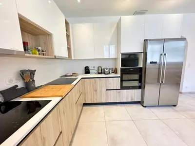 a kitchen with white cabinets and a stainless steel refrigerator at Maison de ville tout confort à Cannes et à 10 Minutes à pied de la plage in Cannes