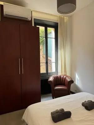 a bedroom with a bed and a chair and a window at Stylish Town House with 3 bedrooms and private parking in Cannes