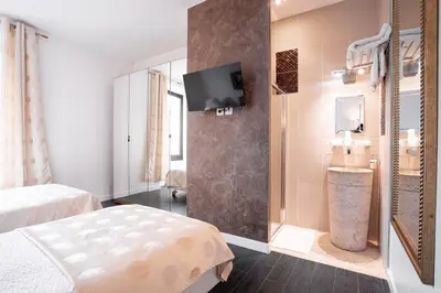 a bedroom with two beds and a tv on a wall at L'EMPEREUR somptueux duplex au style raffiné, Petit Juas, proche du centre in Cannes