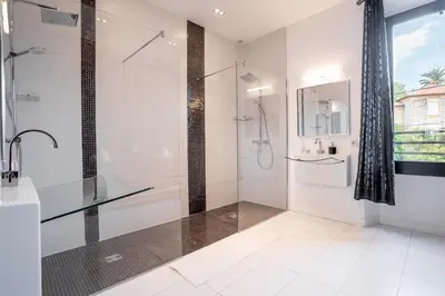 a white bathroom with a shower and a glass shower stall at L'EMPEREUR somptueux duplex au style raffiné, Petit Juas, proche du centre in Cannes