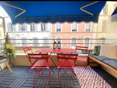 a patio with a red table and chairs on a balcony at Idéal Congrès - 1 min Mer - WIFI - hyper - centre in Cannes