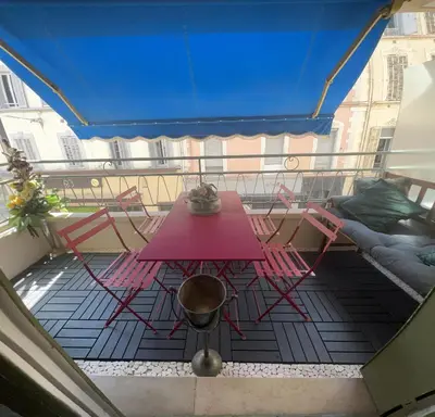 a balcony with a pink table and chairs and a couch at Idéal Congrès - 1 min Mer - WIFI - hyper - centre in Cannes