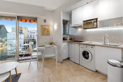 a kitchen with white cabinets and a table and a sink at S 2P CANNES AS - Le Marie Antoinette in Cannes