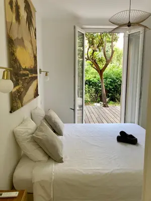 a bedroom with a white bed and a sliding glass door at Cannes - L'Oustaou in Cannes