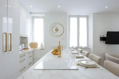 a white kitchen with a long table with plates and bottles at 21 Rue Meynadier - Meynadier 3p in Cannes