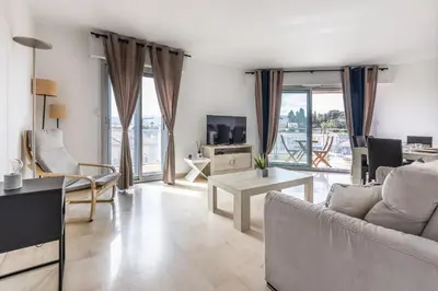 a living room with a couch and a tv at LB Vacation Rentals I High Floor Sea View 2Br Apt with Balcony & Garage in Cannes