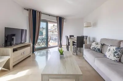 a living room with a couch and a tv and a table at LB Vacation Rentals I High Floor Sea View 2Br Apt with Balcony & Garage in Cannes