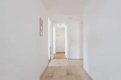 an empty hallway with white walls and wood floors at LB Vacation Rentals I High Floor Sea View 2Br Apt with Balcony & Garage in Cannes
