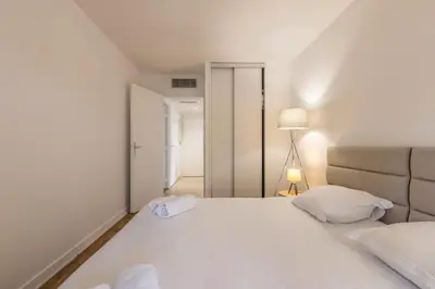 a bedroom with a large white bed and a lamp at LB Vacation Rentals I High Floor Sea View 2Br Apt with Balcony & Garage in Cannes