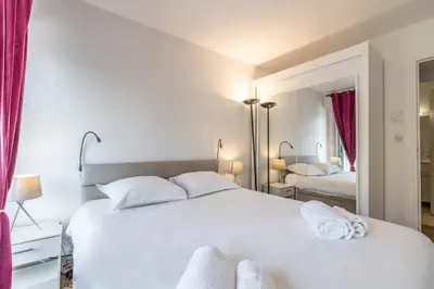 a bedroom with a large white bed and a mirror at LB Vacation Rentals I High Floor Sea View 2Br Apt with Balcony & Garage in Cannes