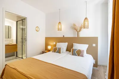 a bedroom with a large bed and a bathroom at L'EMERAUDE duplex confortable au cœur de Cannes, proche plage du Midi et Palais in Cannes