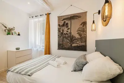 a bedroom with a bed and a painting on the wall at L'EMERAUDE duplex confortable au cœur de Cannes, proche plage du Midi et Palais in Cannes