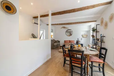 a dining room and living room with a table and chairs at L'EMERAUDE duplex confortable au cœur de Cannes, proche plage du Midi et Palais in Cannes