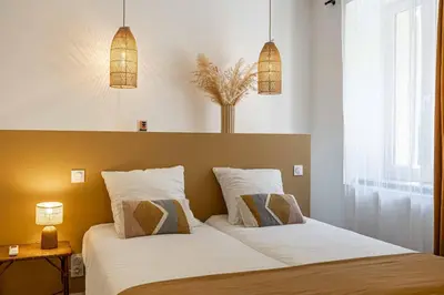 a bedroom with a bed with two pillows and two lights at L'EMERAUDE duplex confortable au cœur de Cannes, proche plage du Midi et Palais in Cannes