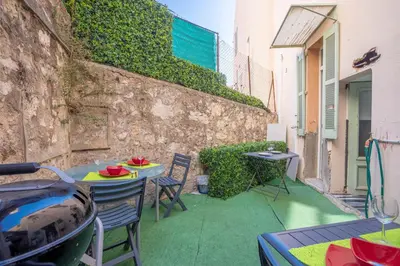 a patio with a table and chairs and a wall at Cannes Experience Pastour Privatize 6 aparts 10bedrooms&9baths 11doublebeds with his duplexpenthouse ROOFTOP close palais congres beaches et Suquet in Cannes