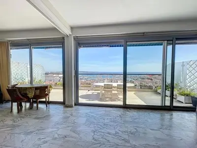 a living room with a table and glass doors at AGENCIA dernier étage vue mer panoramique in Cannes