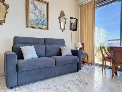 a blue couch in a living room with a window at AGENCIA dernier étage vue mer panoramique in Cannes