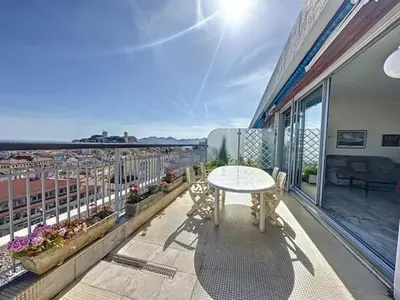a balcony with a table and a view of a city at AGENCIA dernier étage vue mer panoramique in Cannes