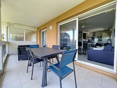 a dining room with a table and chairs and a living room at Cannes - 2 pièces résidence avec parc et piscine in Cannes
