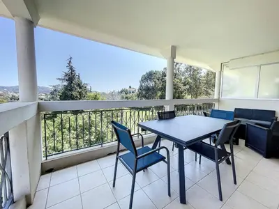 a balcony with a table and chairs and a view at Cannes - 2 pièces résidence avec parc et piscine in Cannes