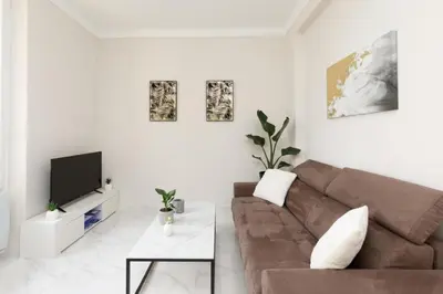 a white living room with a brown couch and a tv at Bright and elegant renovated two rooms - Near Suquet in Cannes