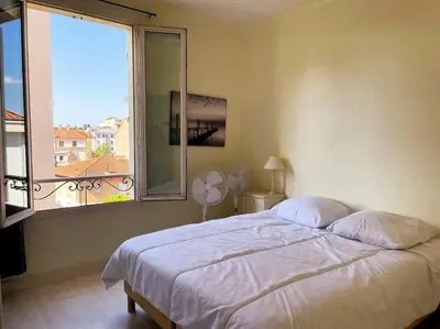 a bedroom with a bed and a large window at C043-Agréable 3 Pièces proche Croisette et plages in Cannes