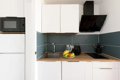 a kitchen with white cabinets and a bowl of fruit on the counter at Chagall 3 étoiles in Cannes