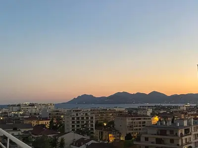 a city skyline at sunset with mountains in the background at Le somptueux Le Gallia in Cannes